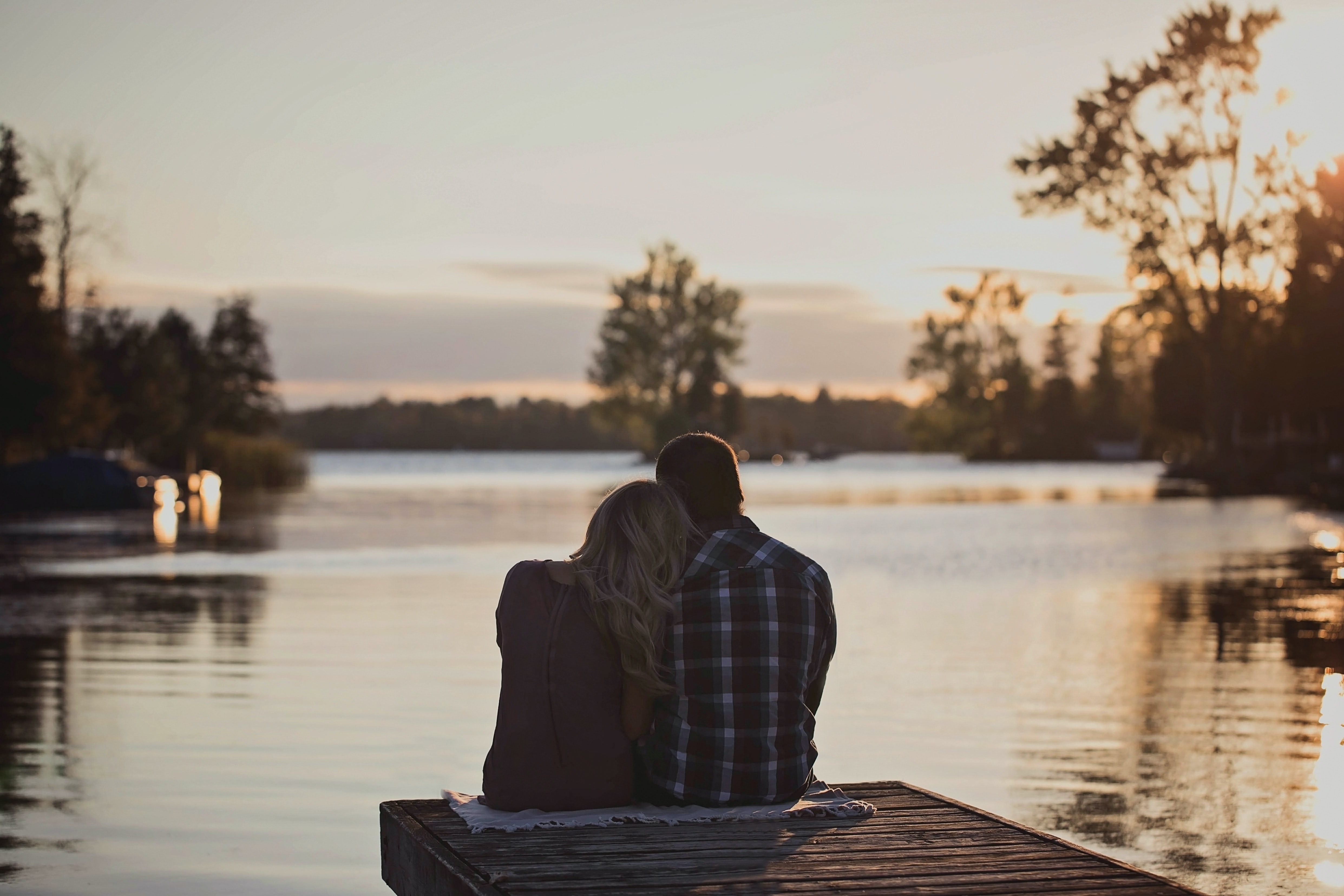 A Man And Woman setting on dock during golden hours
