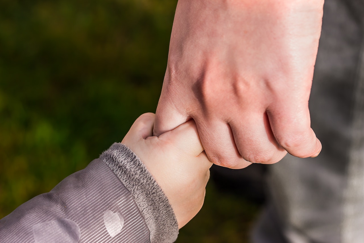 Child holding hand of another man