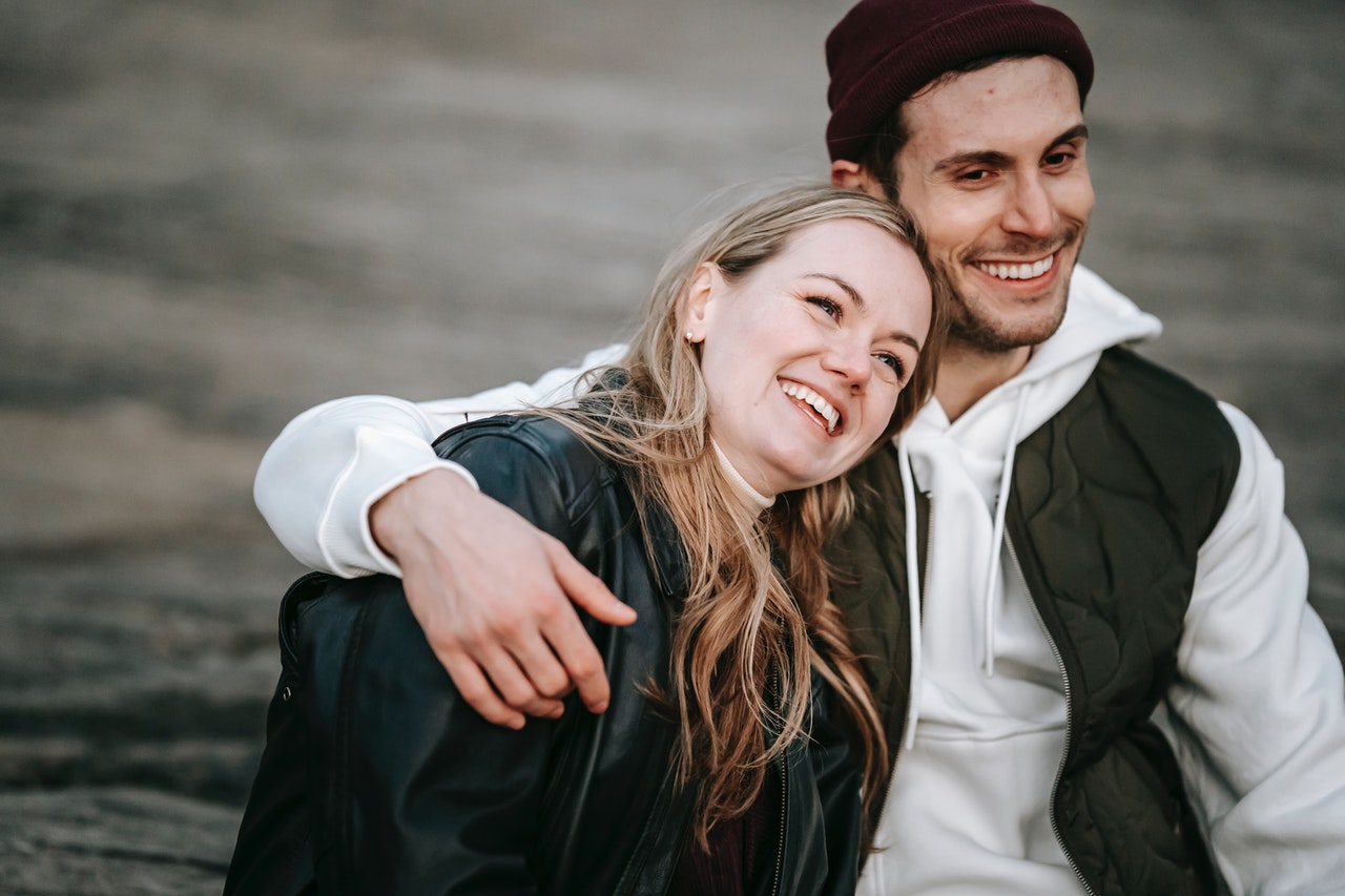Happy man embracing girlfriend both wearing jacket
