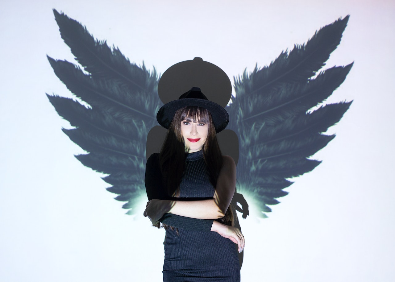 Elegant woman standing near wall with wings