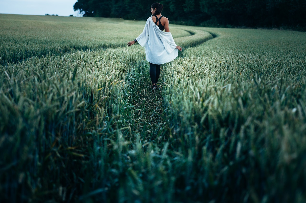 Woman Walking in the Rice Plant Field during Daytime