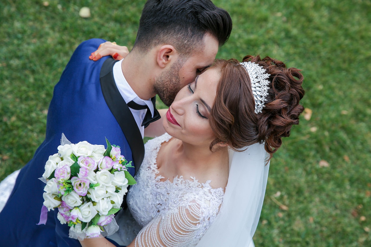 Bride holding flower while groom embraces her