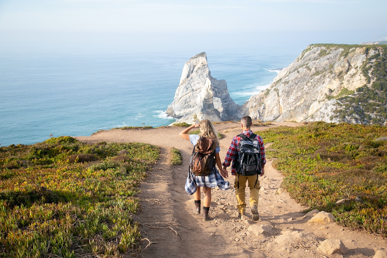 Couple walking holding hands on a trail overlooking the sea