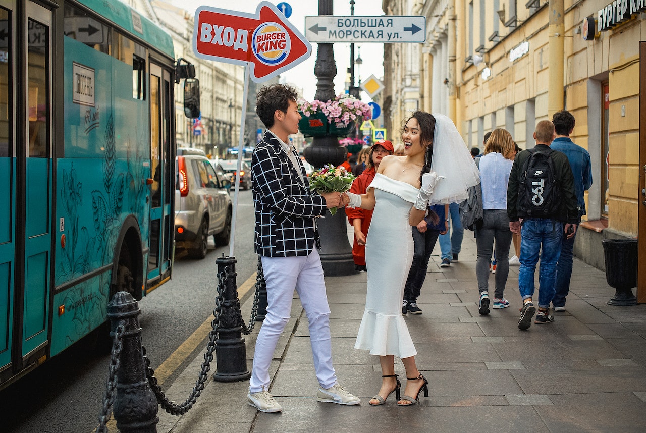 Man in a checkered blazer holding a bouquet of flowers with a woman in a wedding dress