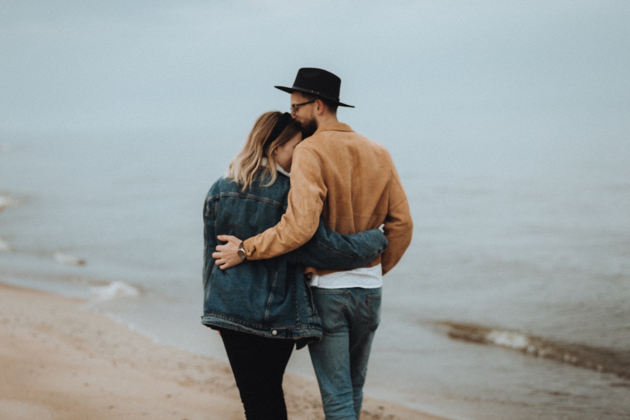 A Man Kissing Woman while Standing on the Beach